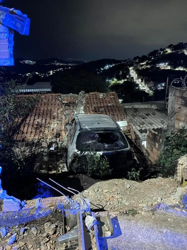 Carro bate em muro e fica pendurado sobre telhado de casa em Sabará